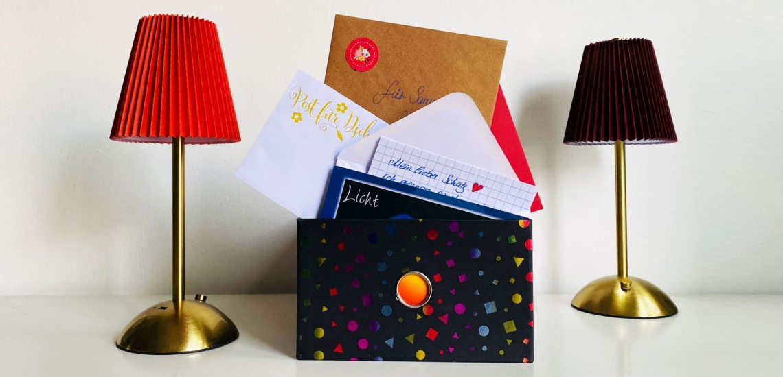 Kiste mit Briefen, daneben zwei Stehlampen