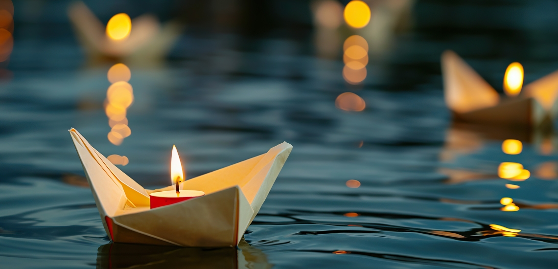 Selbst gefaltete Papierboote mit Teelichtern schwimmen übers Wasser.