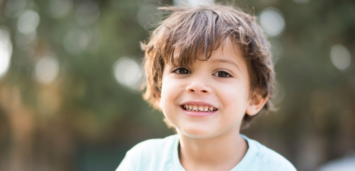 Kind mit strubbeliger Frisur nachdenklich schauend in Natur