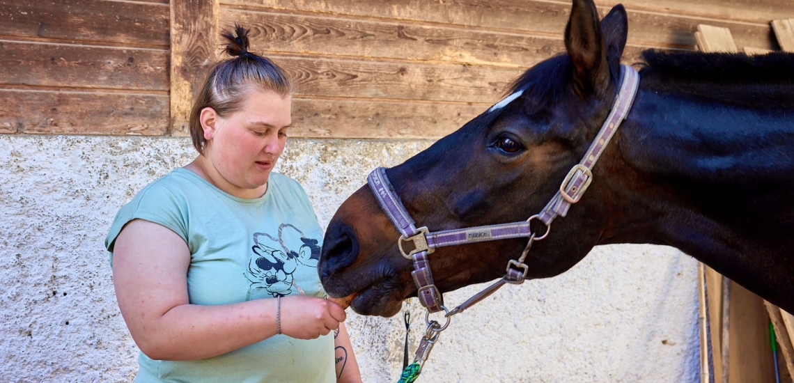 Junge Frau gibt Pferd eine Möhre zu fressen