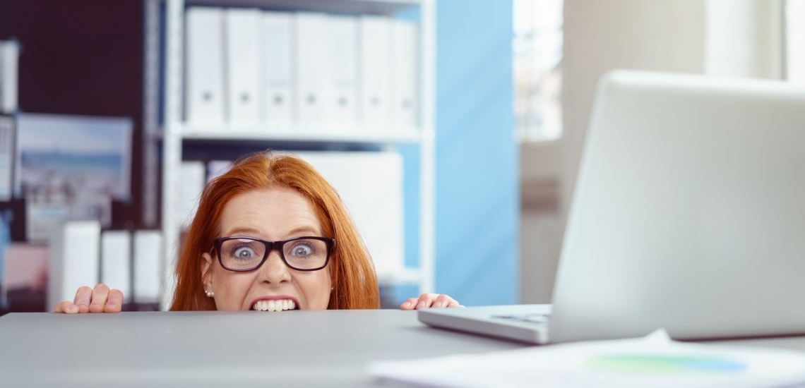 Frau in Büro beißt vor Verzweiflung in Schreibtischkante