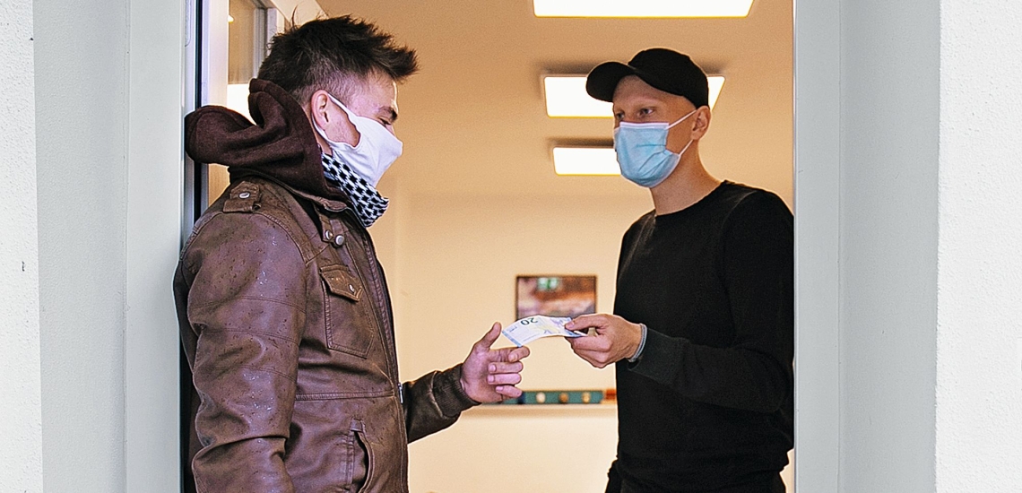 Junger Mann nimmt Geld von Mitarbeiter in Empfang 