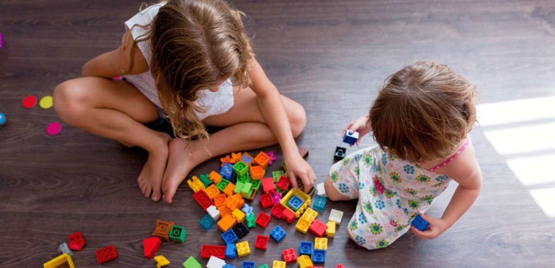 Zwei Schwestern spielen mit Legosteinen 