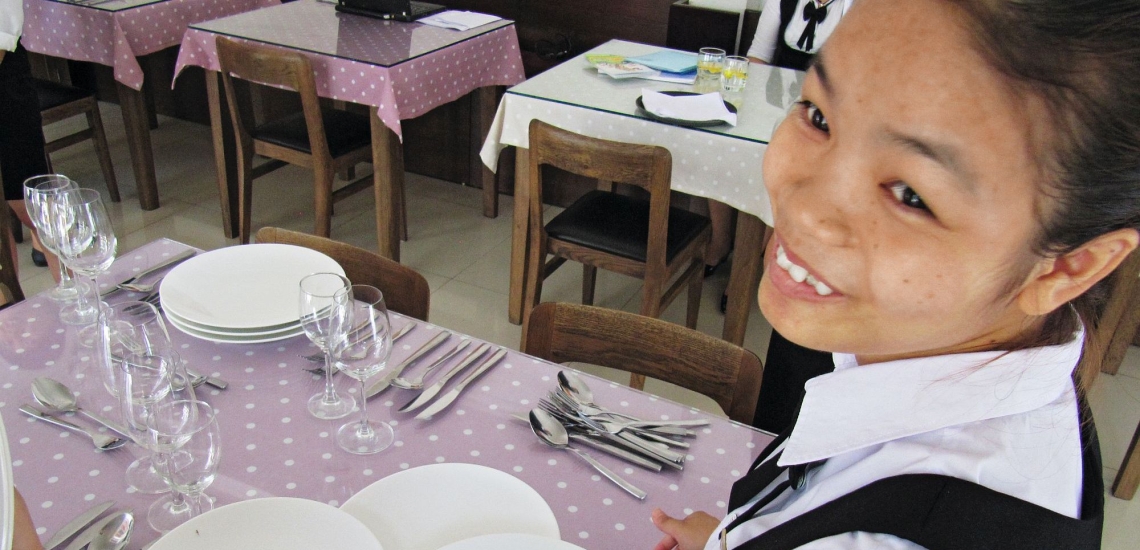 Junge Frau übt Servieren in Don Bosco Hotelfachschule in Vietnam 