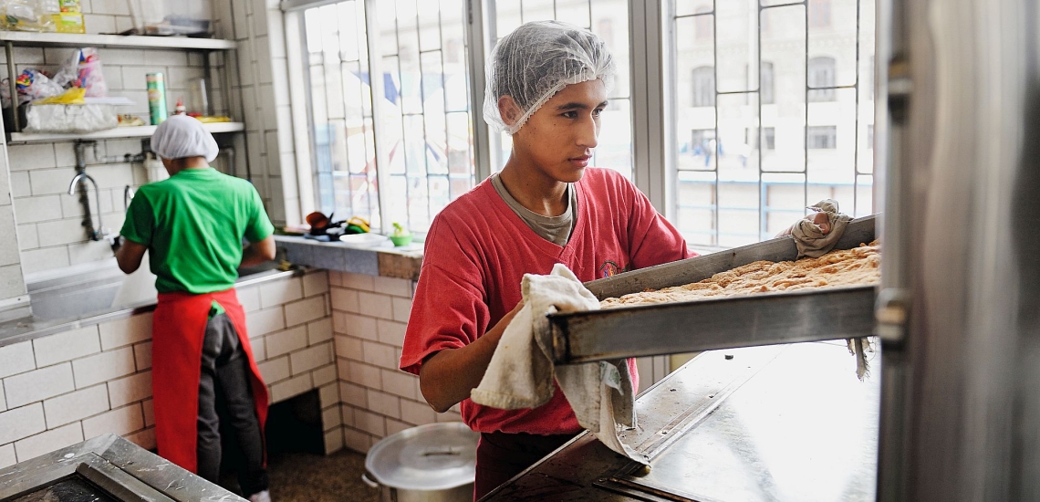 Jugendlicher holt Blech aus Ofen 