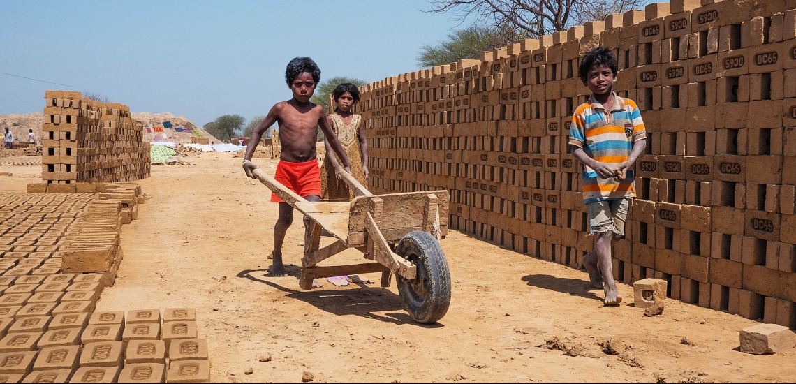 Kinder mit Schubkarre auf Ziegelfeld in Indien