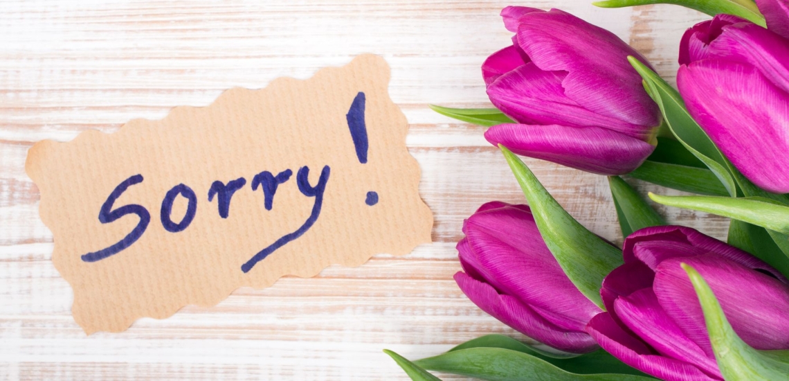 Tulpenstrauße neben Schild mit Aufschrift Sorry 