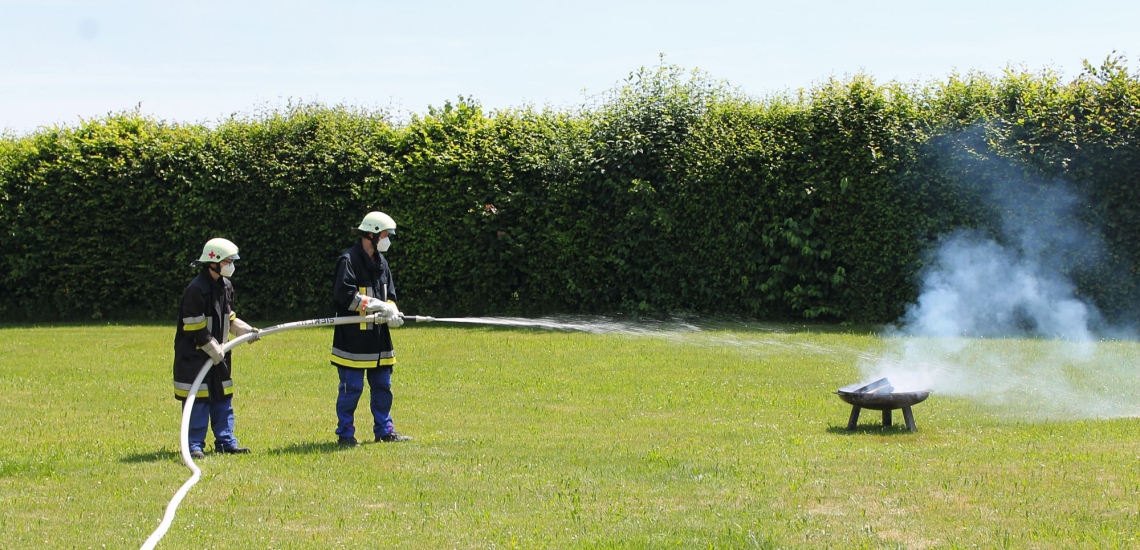 Zwei Feuerwehrleute löschen Brand in Feuerschale 