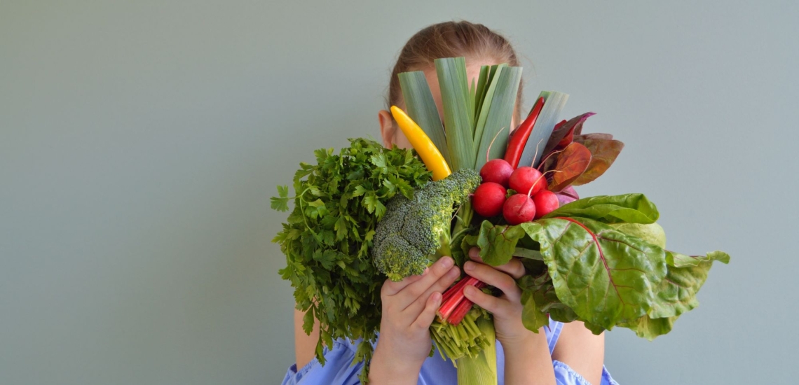 Jugendliche hält sich Gemüse vor das Gesicht