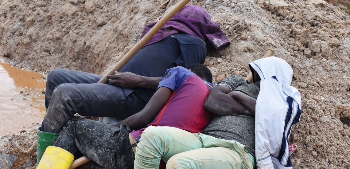 Menschen mit über den Kopf gezogenen Kapuzen liegen im Schlamm