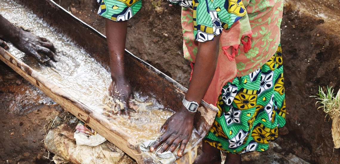 Frau wäscht Erz in Wasser