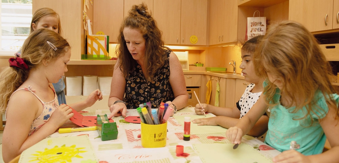 Kinder und Pädagogin an Basteltisch 