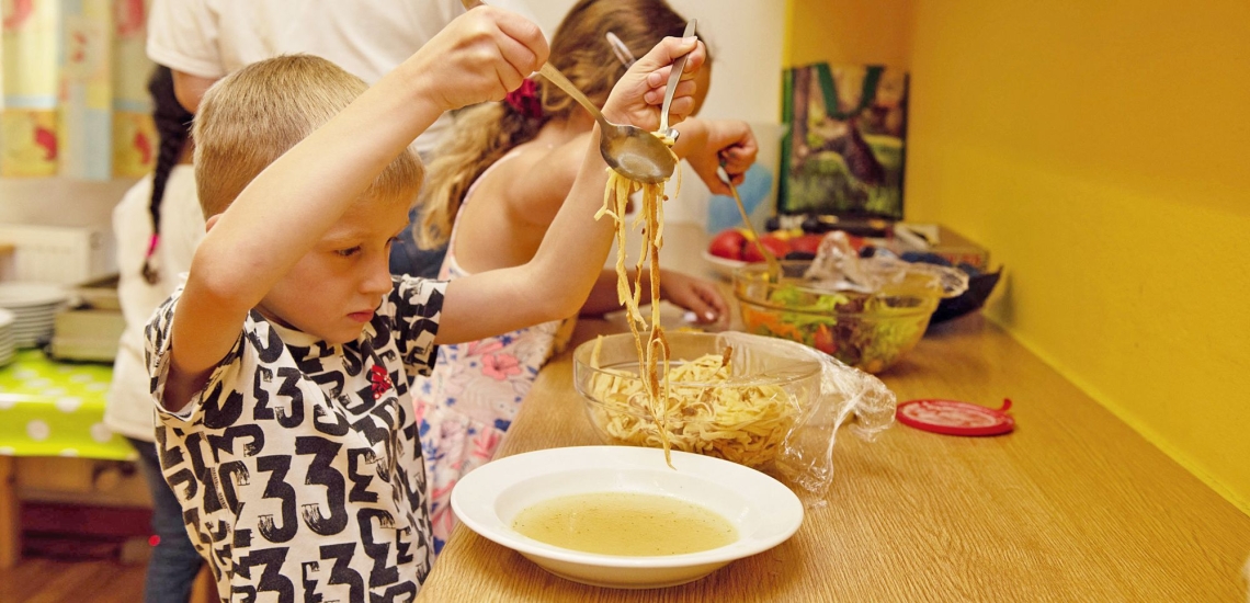 Junge nimmt sich Essen aus einer Schüssel 