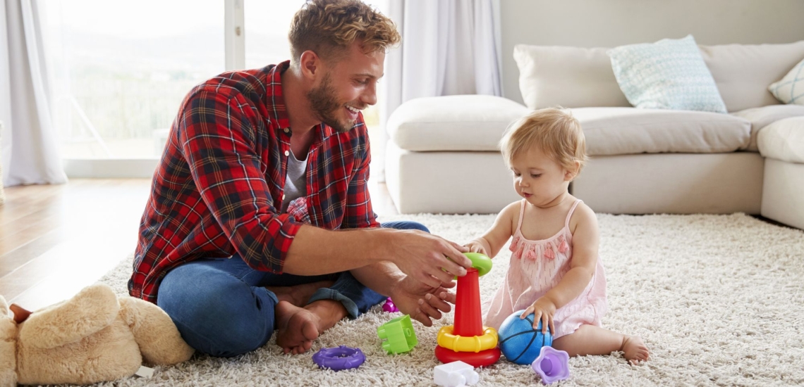 Vater spielt mit kleiner Tochter im Wohnzimmer