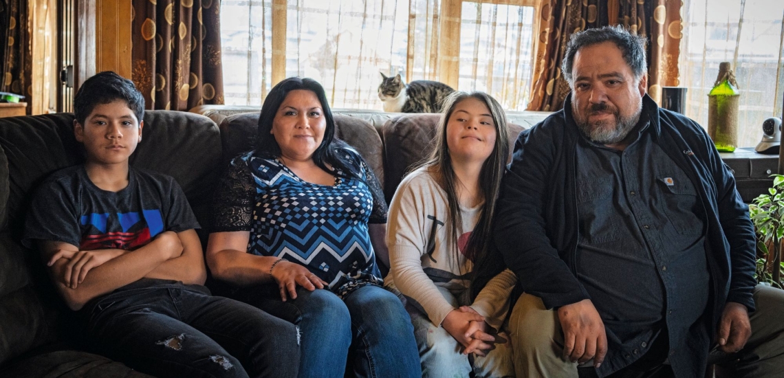 Vater, Mutter und zwei Teenager sitzen auf Sofa