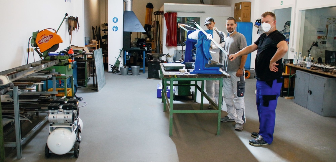 Anleiter mit zwei jungen Männern in der Metallwerkstatt der Manege von Don Bosco Berlin 