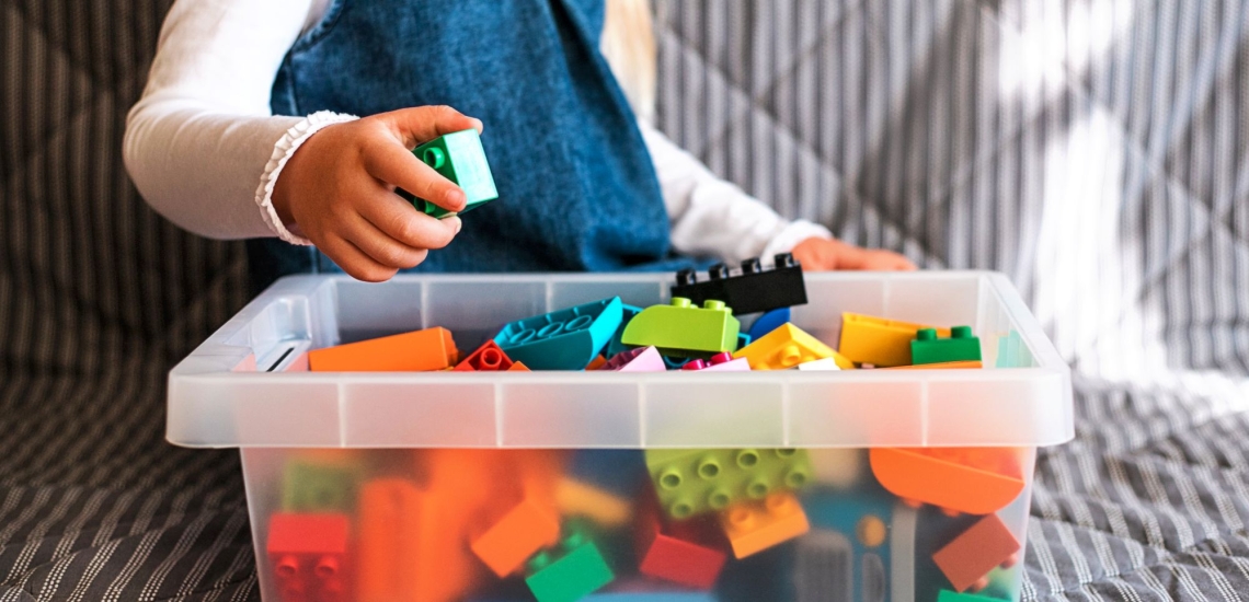 Kind sortiert Legosteine in Kiste 