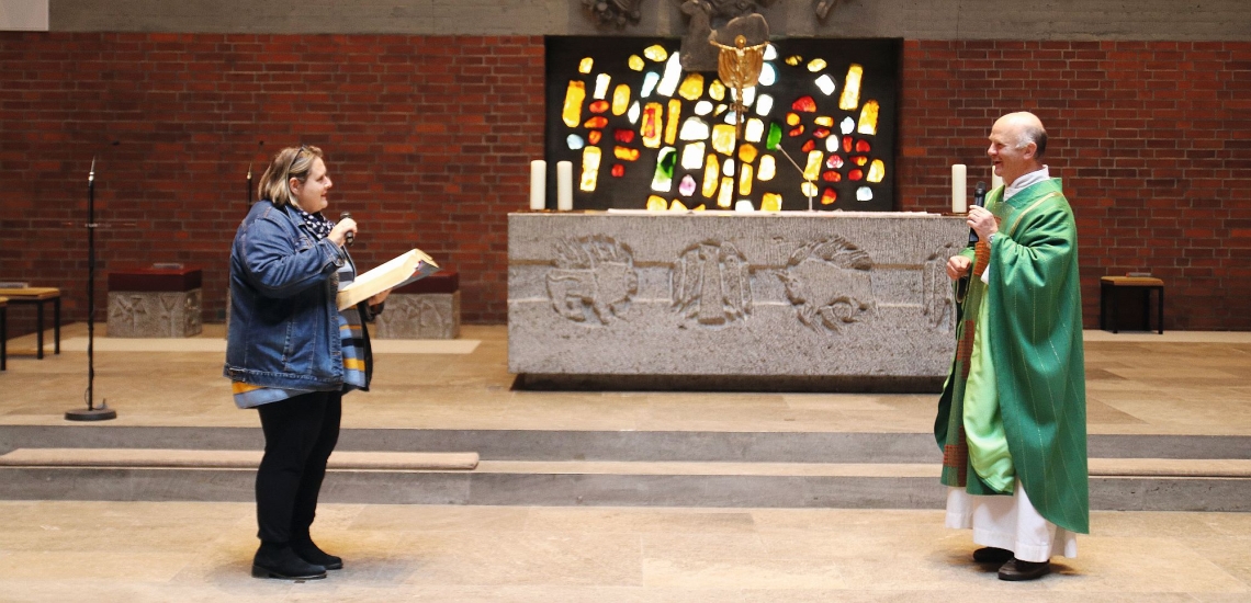 Frau und Priester im Altarraum einer Kirche 