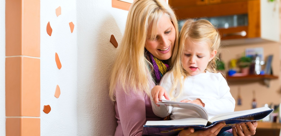 Mutter und Kind lesen zuhause in einem Buch 