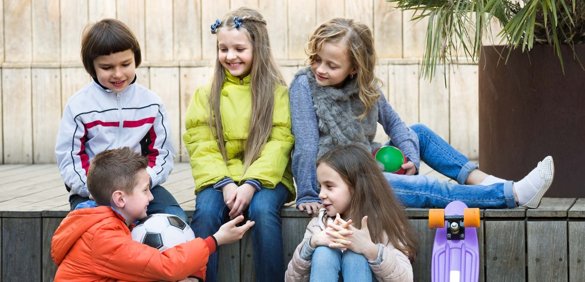 Eine Gruppe Kinder sitzt draußen und unterhält sich.