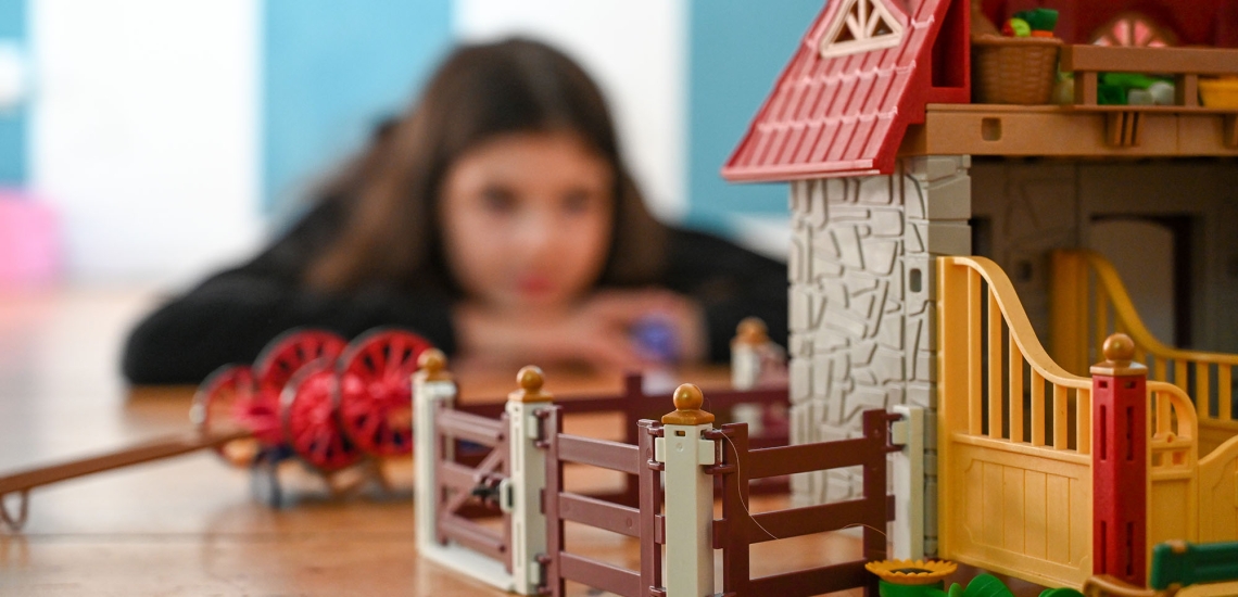 Ein Mädchen sitzt vor einem Playmobil-Stall.