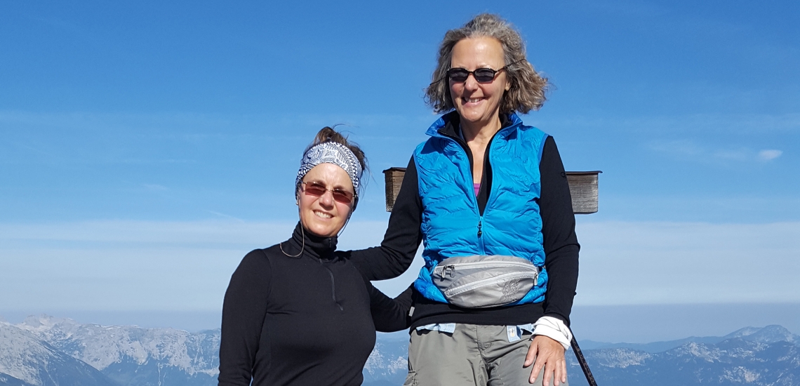 Die Freundinnen Angelika und Heike stehen vor einem Gipfelkreuz.