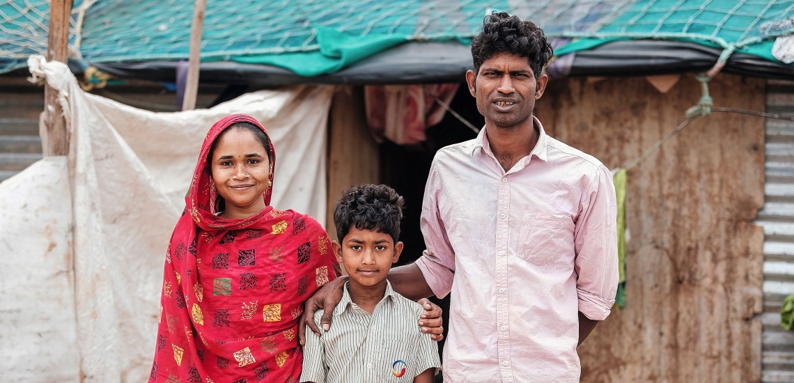 Junge glücklich mit Eltern vor Hütte in Indien 