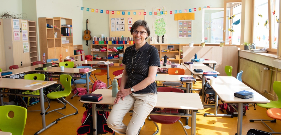 Schwester Ulrike Weiss sitzt auf Tisch in Klassenzimmer der Volksschule 