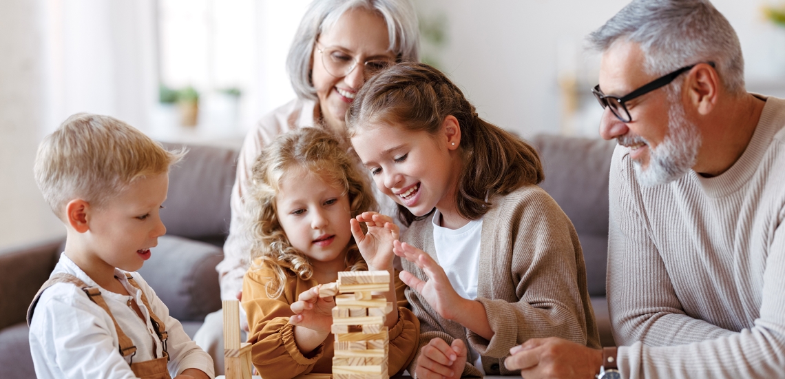 Großeltern spielen mit ihren drei Enkelkindern Jenga.