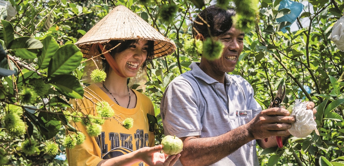 Frau und Mann mit Früchten in der Natur in Vietnam