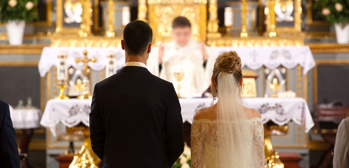Brautpaar in Kirche während Priester am Altar betet 