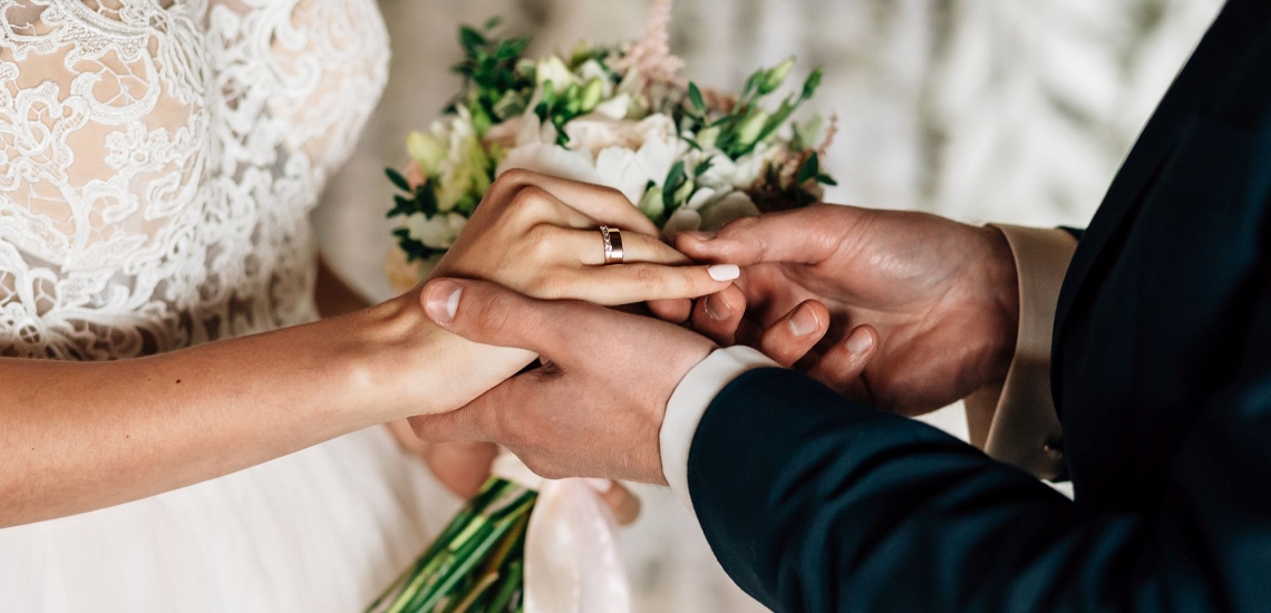 Der Bräutigam steckt der Braut den Ring an den Finger 
