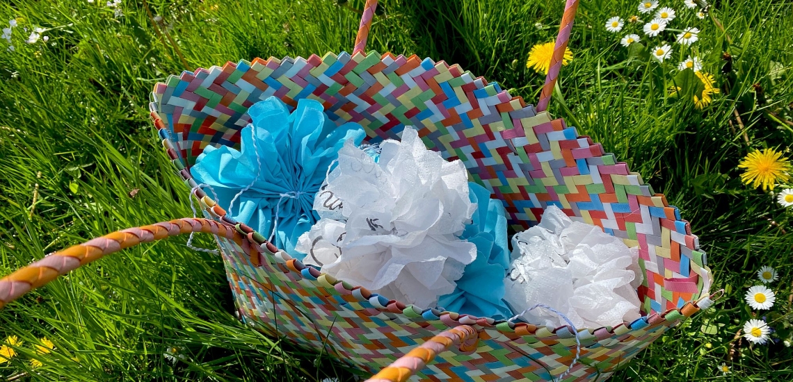 Blaue und weiße Pompons in buntem Flechtkorb auf Wiese für Hochzeitsfest 