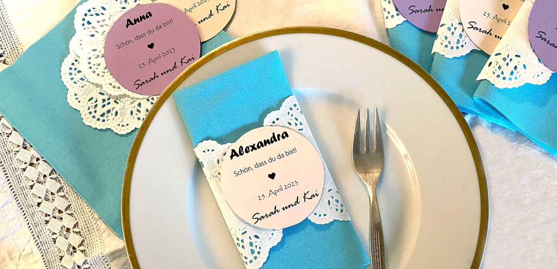 Hübsch verzierte Tischkarte aus Papier und Spitze und mit Namen ist um Serviette gelegt auf Hochzeitstisch 