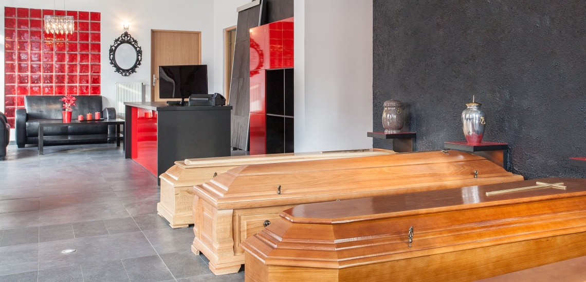 Särge, Urnen, Schreibtisch und Besprechungsecke in einem modern wirkenden Bestattungsinstitut 