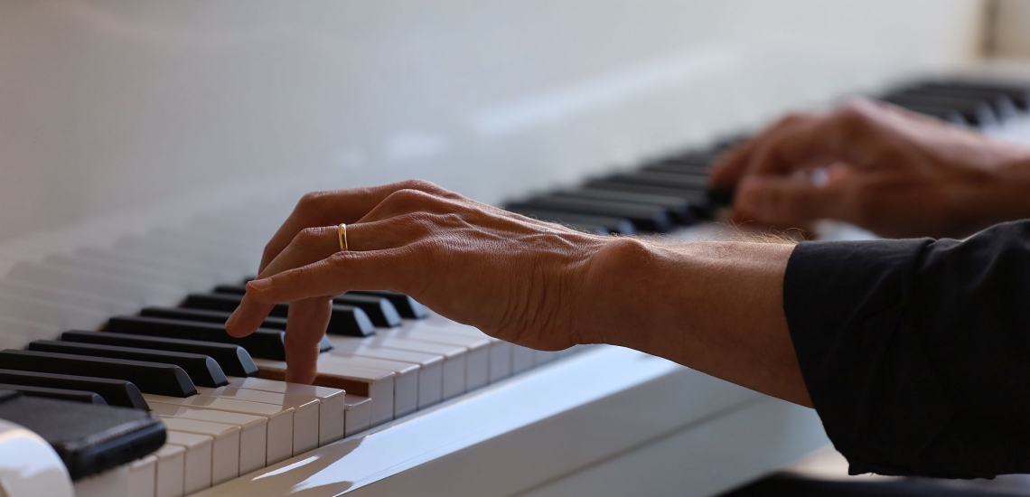 Hände spielen auf einem weißen Klavier 