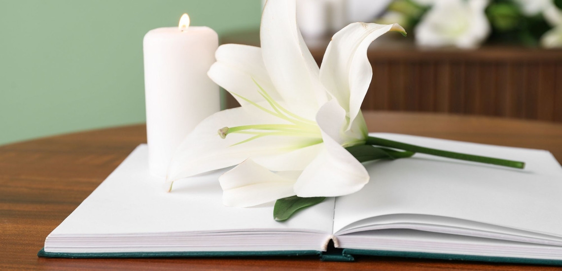 Geöffnetes Notizbuch mit brennender Kerze und weißer Lilie 