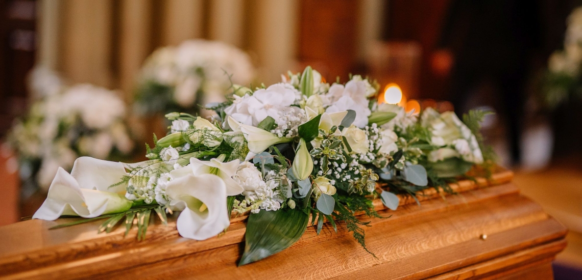 Mit weißen Blumen geschmückter Sarg in einer Kirche 