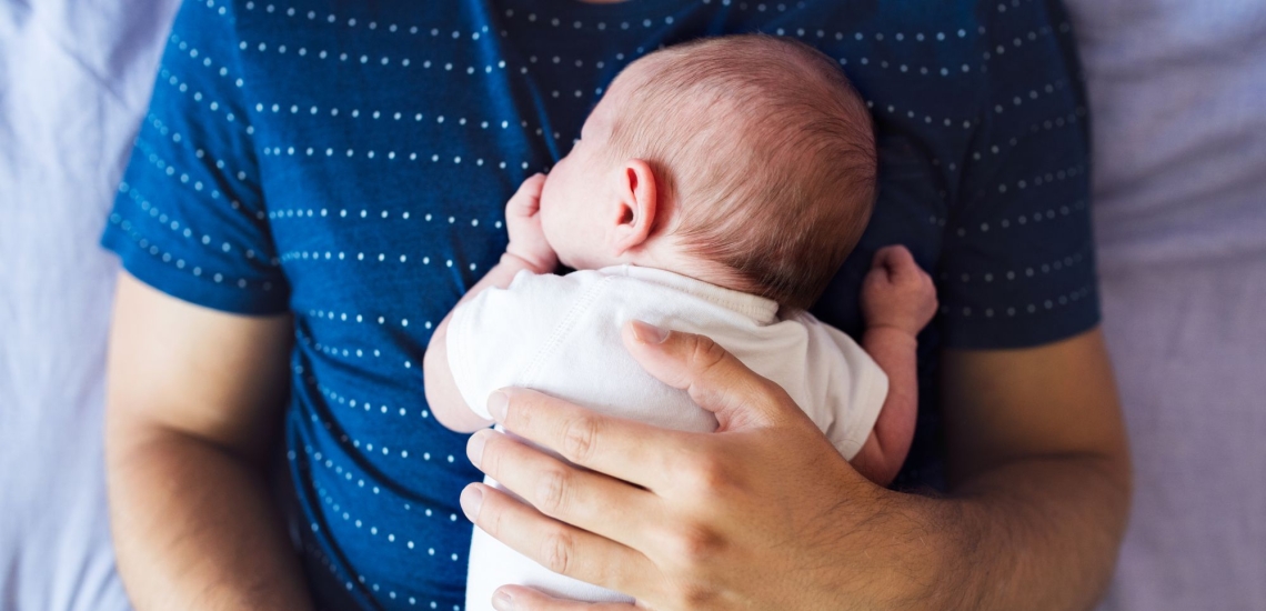 Baby liegt auf Bauch des Vaters 