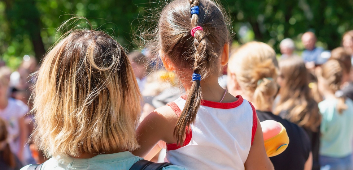 Mutter und Kind in Menschenmenge bei Veranstaltung im Freien 