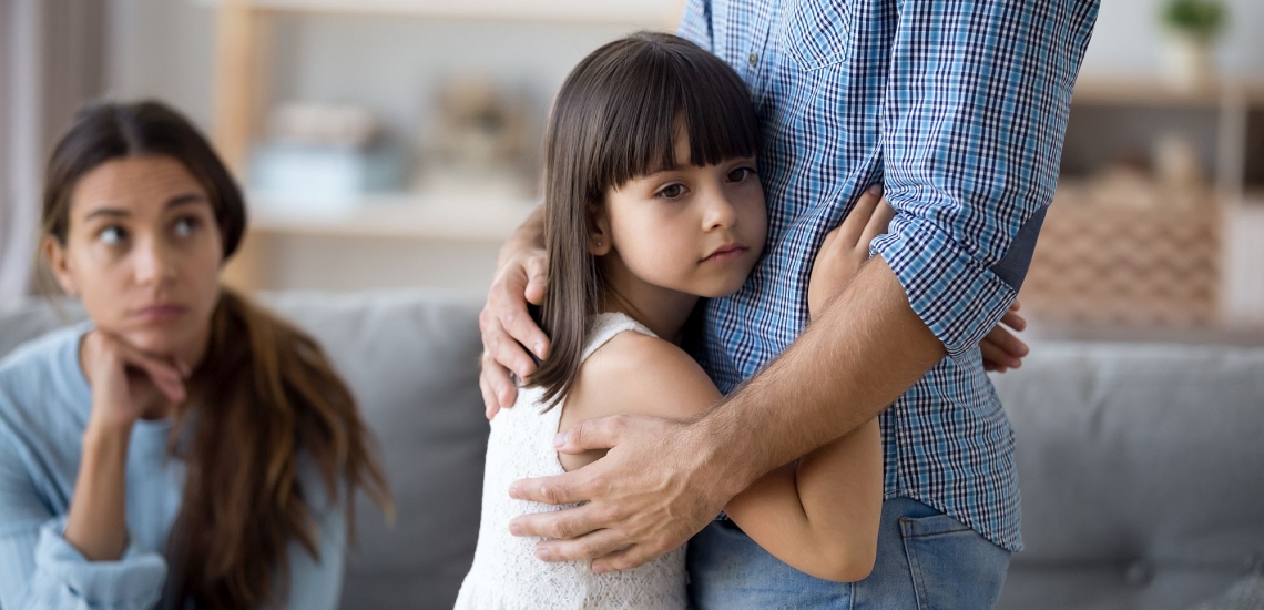 Kind umarmt Vater, während Mutter auf der Couch sitzt 