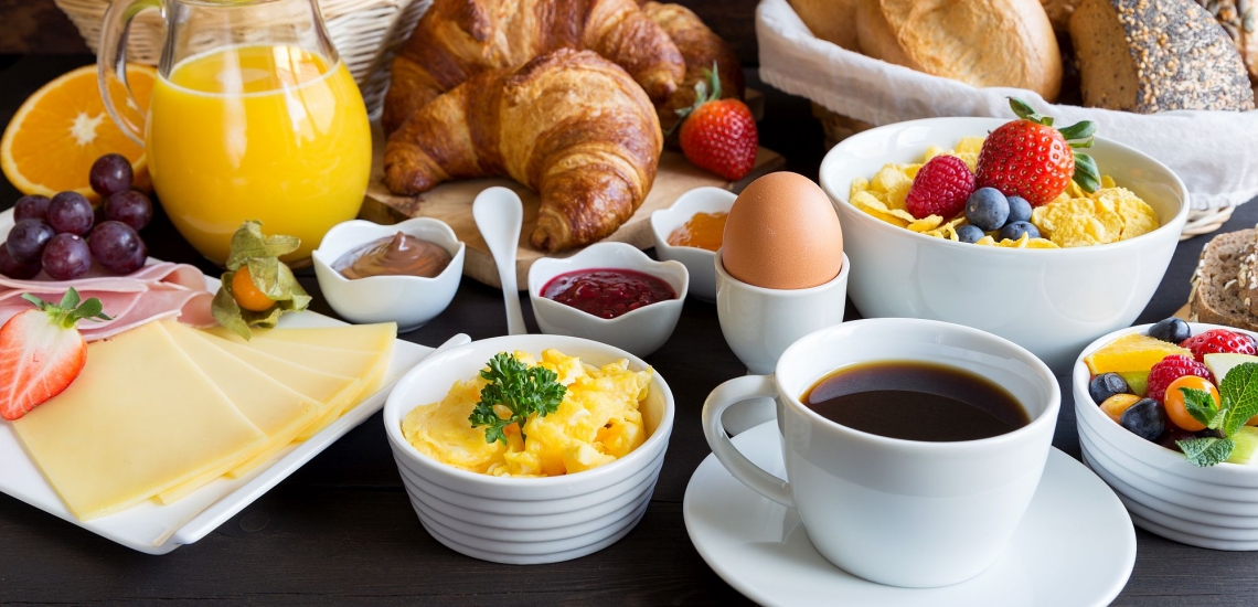Frühstückstisch mit Obst, Saft, Kaffee, Brötchen, Marmelade und Eiern 