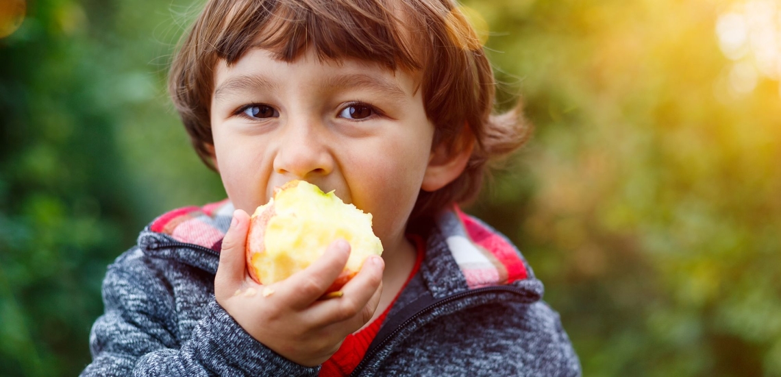Kind isst genussvoll Apfel in Natur 