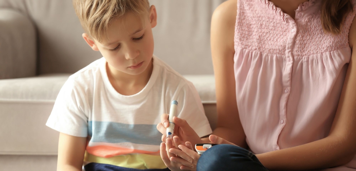 Junge und Mutter messen Insulin am Finger des Kindes 