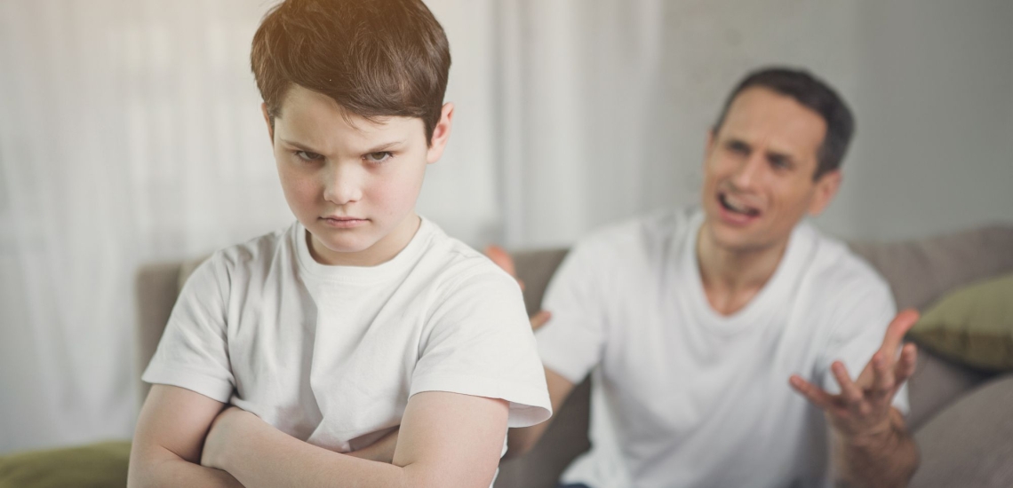 Vater redet wütend auf Jungen ein, der wendet ihm trotzig den Rücken zu 