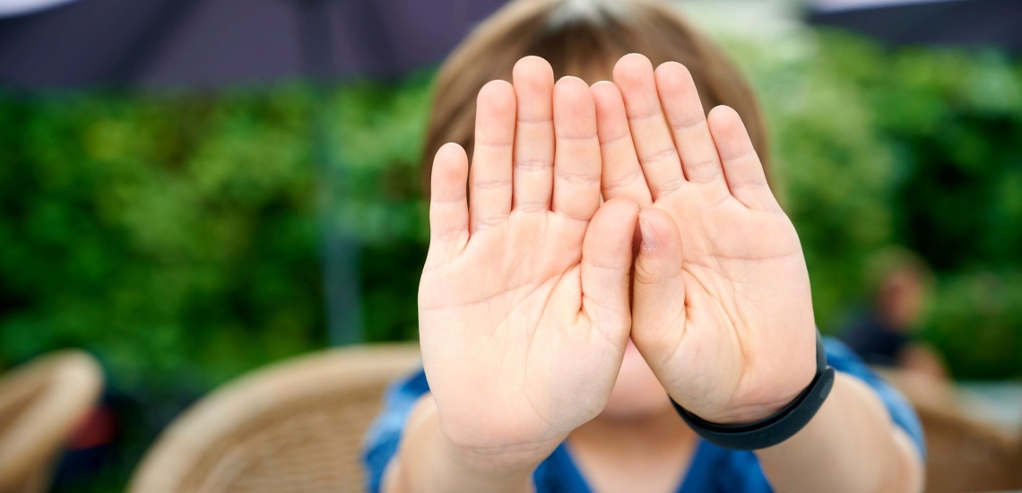 Kinderhände in Abwehrhaltung vor dem Gesicht