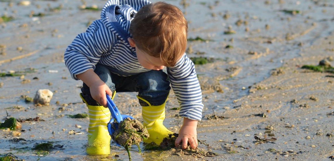 Kind spielt mit am Strand mit Sand 