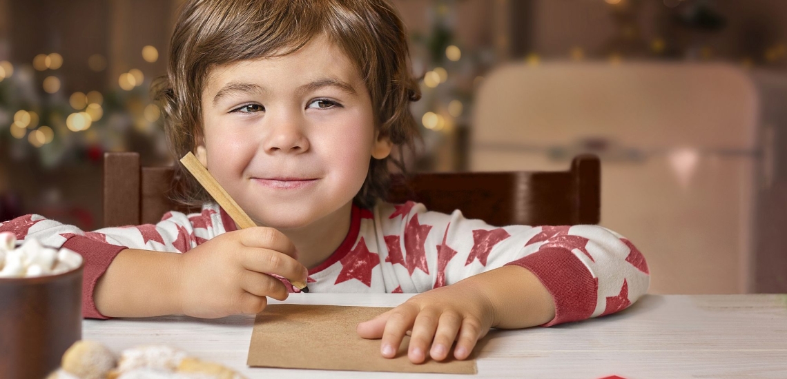 Junge schreibt Wunschzettel für Weihnachten und denkt über das Christkind nach 