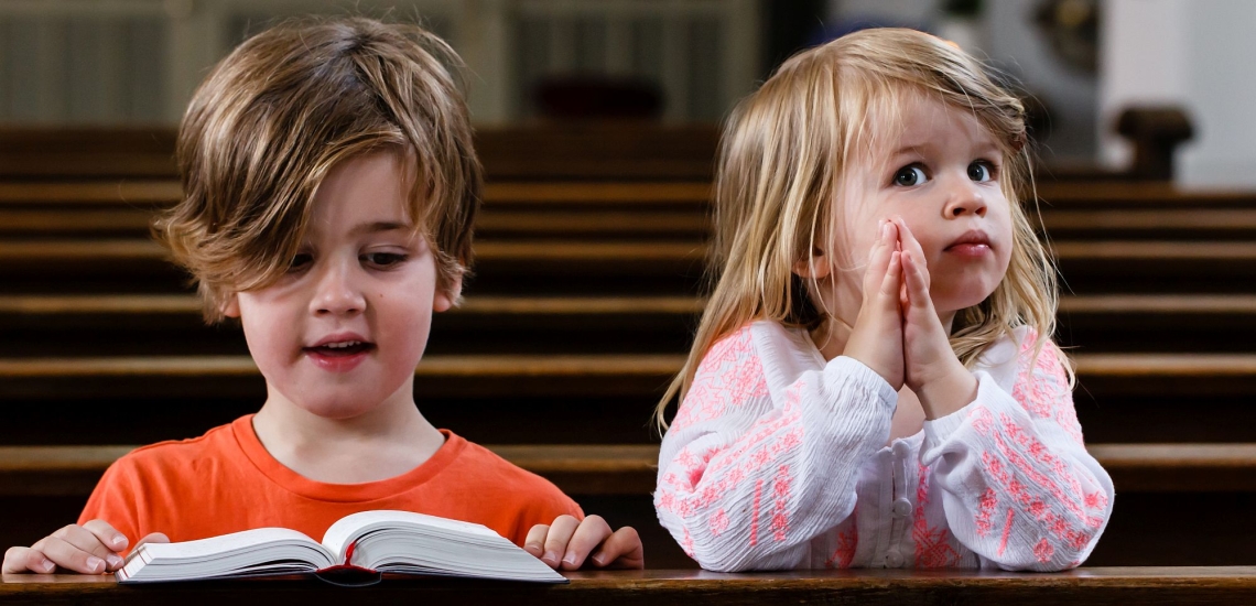 zwei Kinder sitzen in Kirchenbank