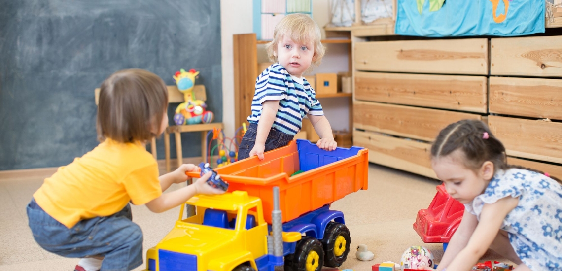 Kinder streiten in der Kita um einen Spielzeuglastwagen 